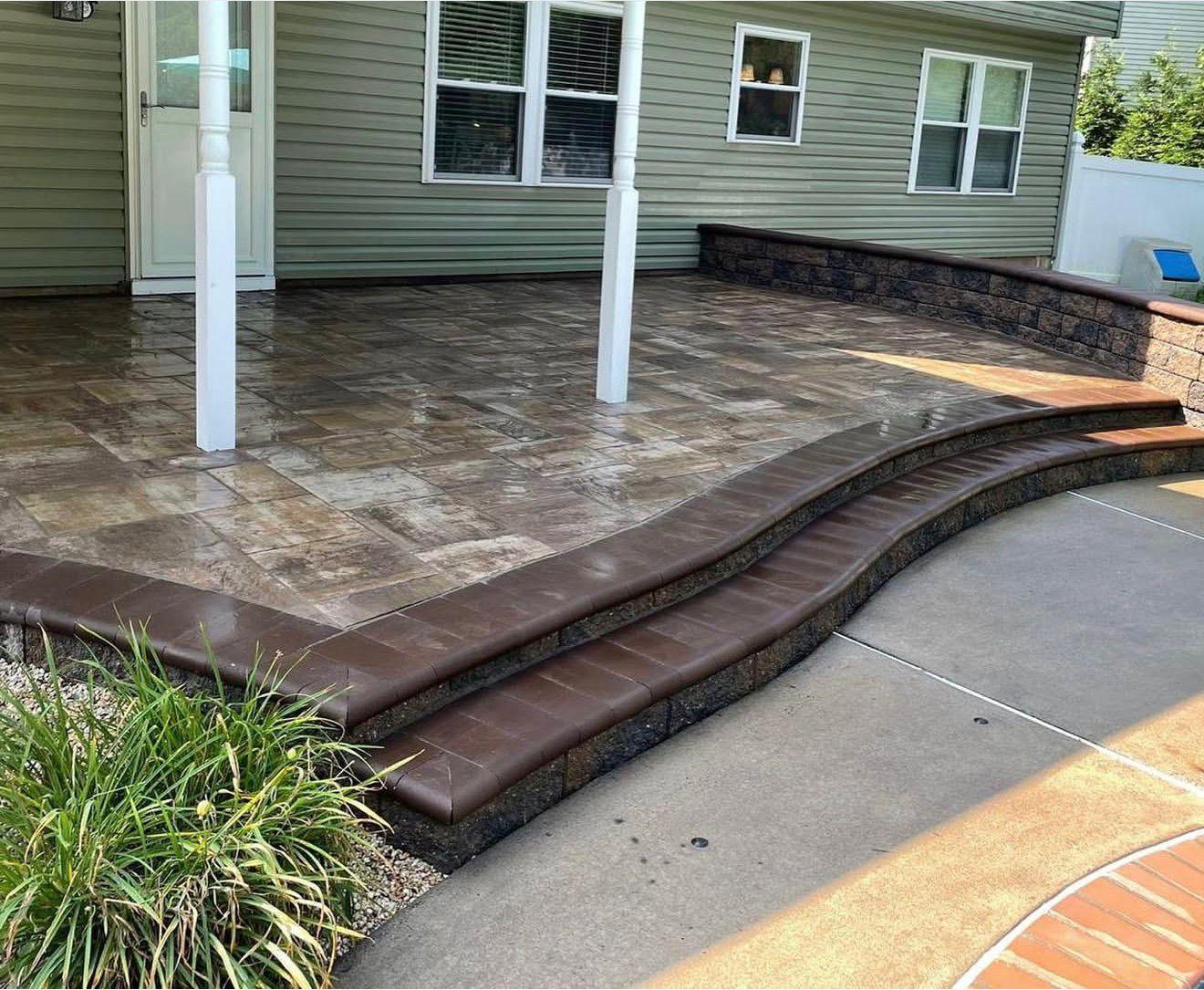 Paver patio with curved steps and a low retaining wall