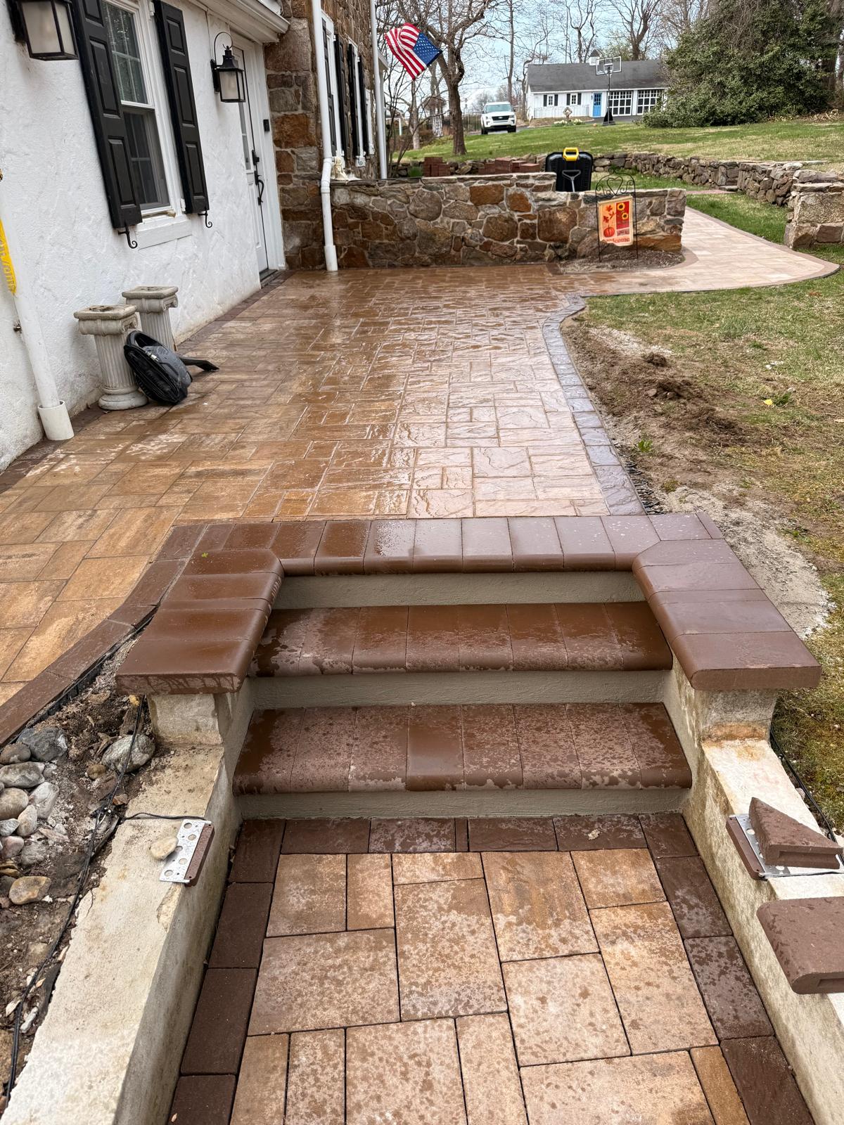Stamped concrete patio with paver steps and a stone wall